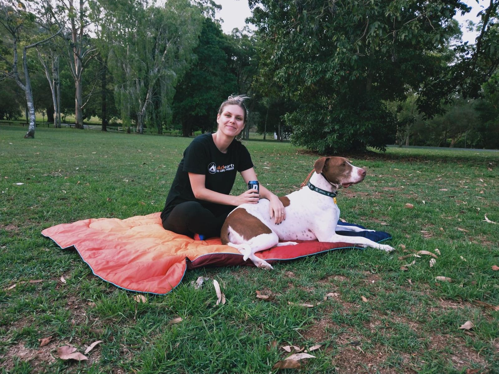 Abby sitting on an orange picnic blanket with her dog, Gus