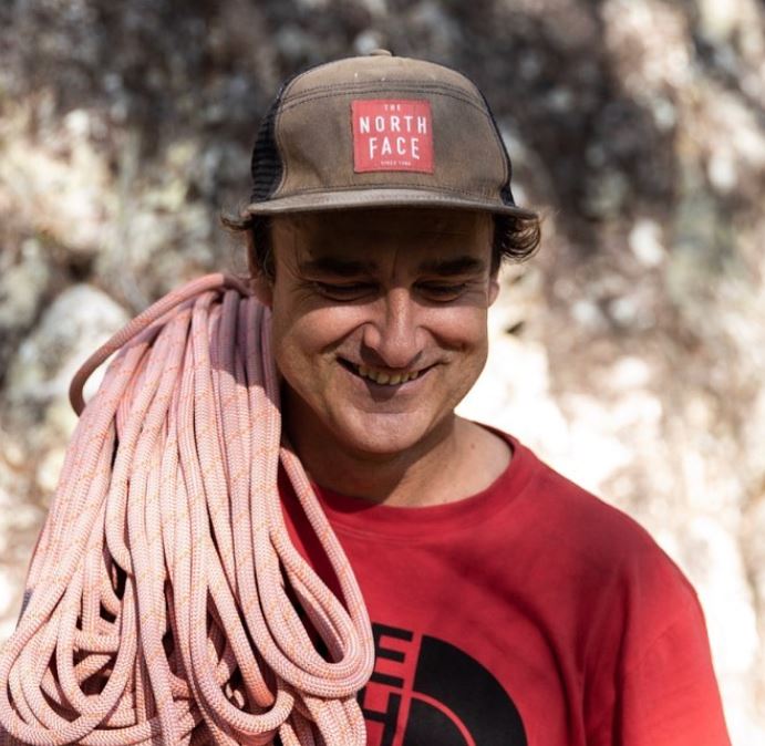 Christian wearing a The North Face cap with climbing rope over his right shoulder