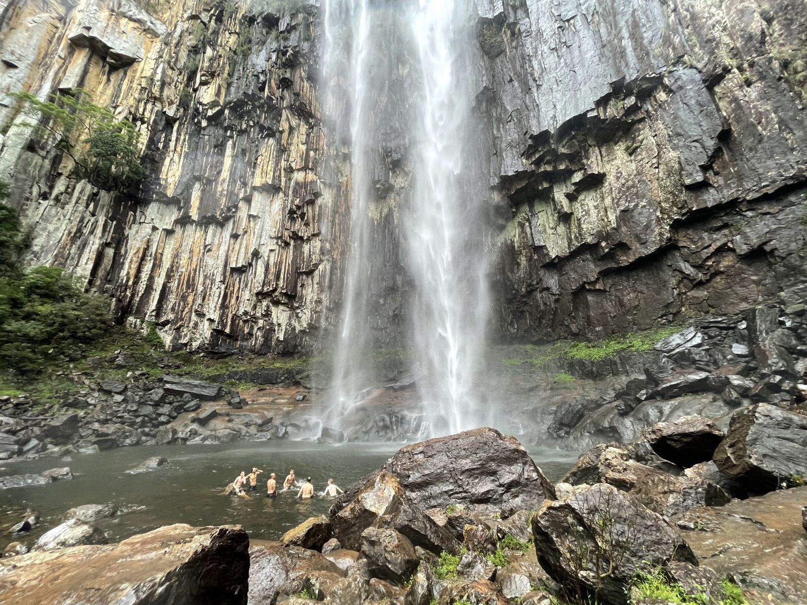 Young people swimming under a waterfall