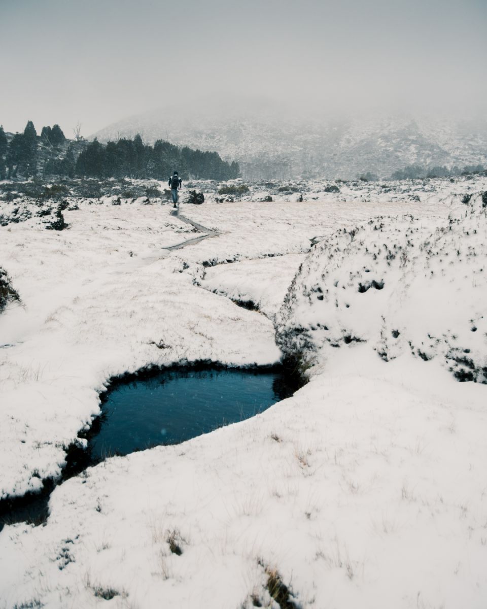 Hiker on snow covered track in the mountains