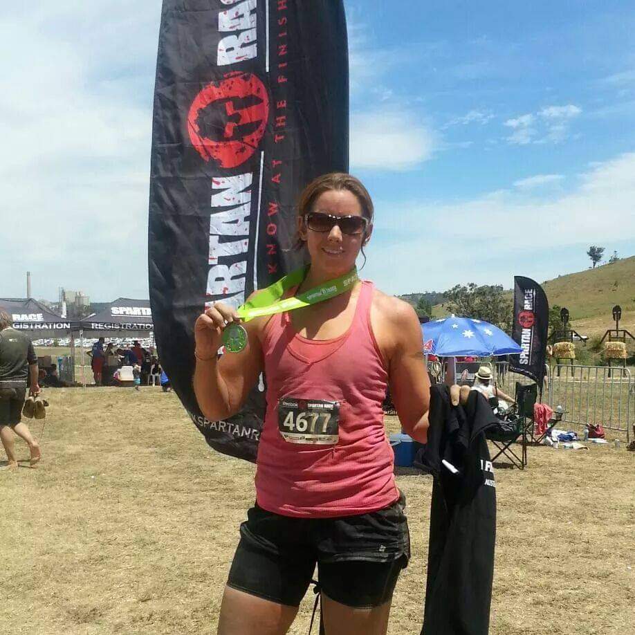 Dani at the finish line in front of a Spartan Event flag 