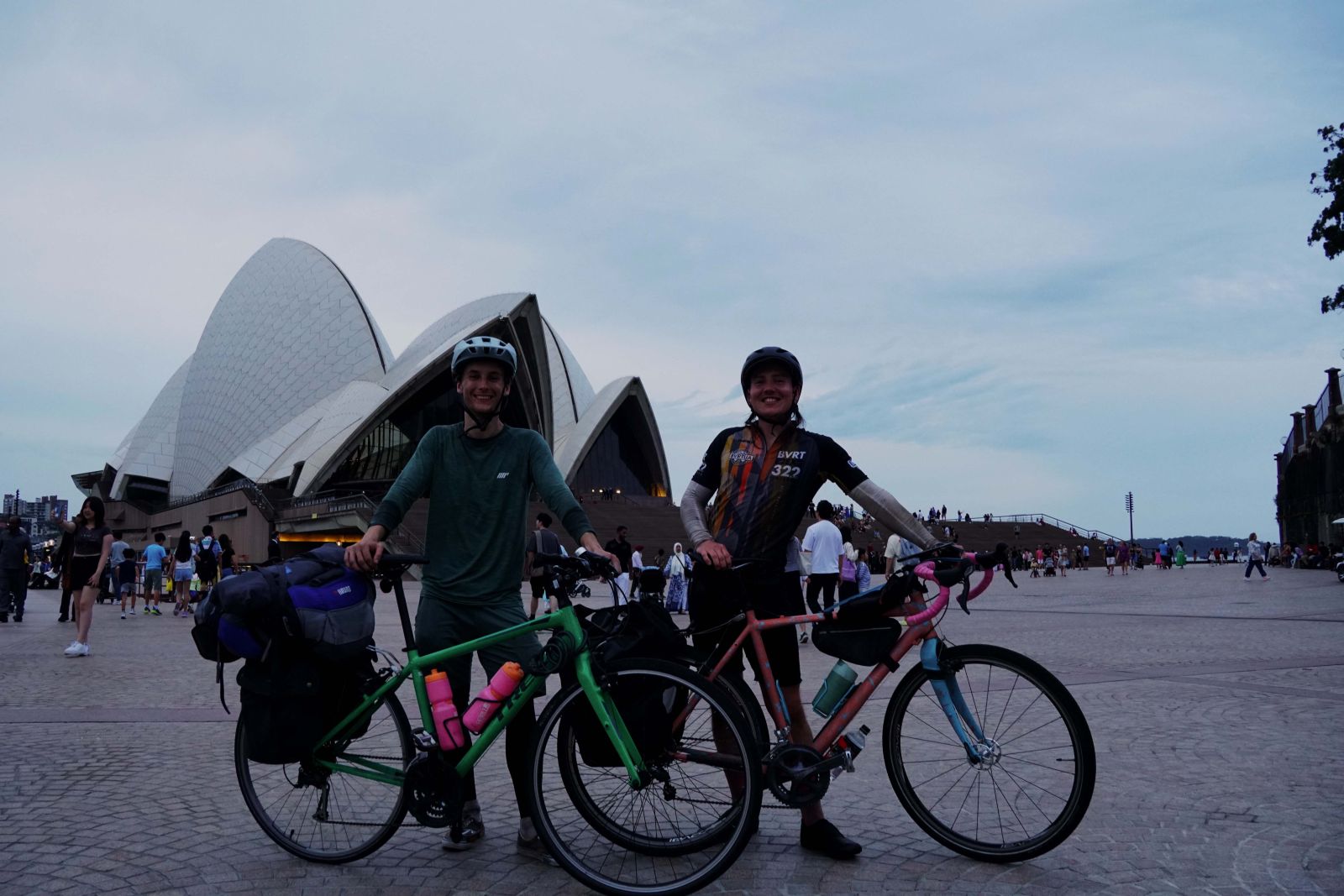 James and Reid in front of the Sydney Opera House with their bikes