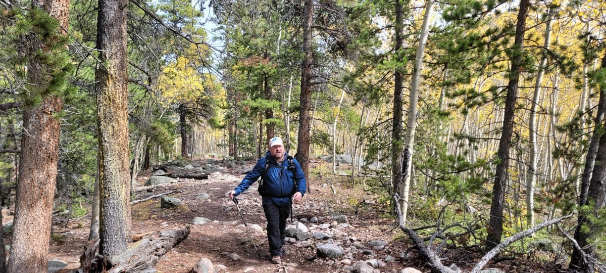 A man in hiking gear along a forested trail