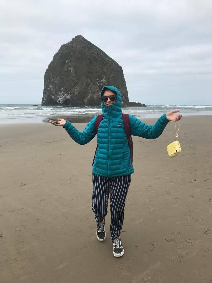 Jess at Cannon Beach wearing the Patagonina Down Hoody with the hood up