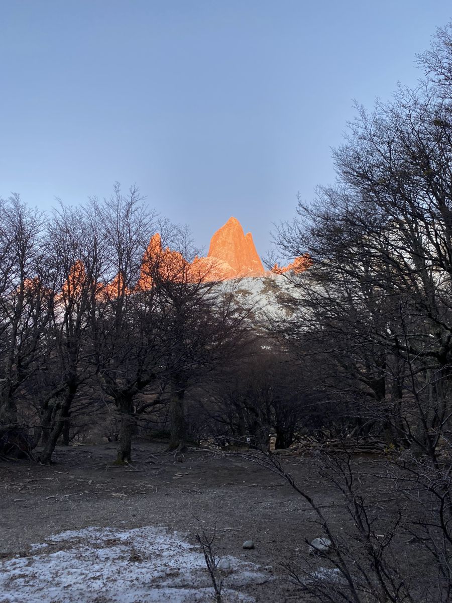View of Mount Fitz Roy at sunrise lit in orange. 