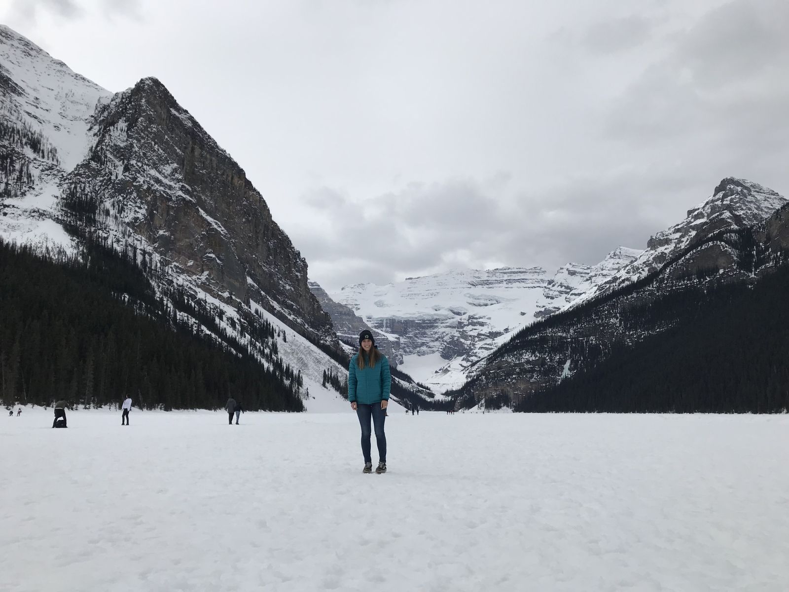 Jess on a frozen Lake Louise with mountains in the background wearing the Patagonia Down Hoody