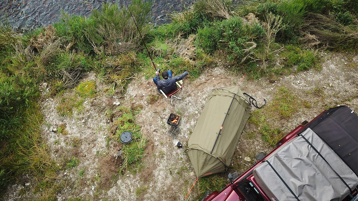 Man fishing next to his swag and 4WD car.