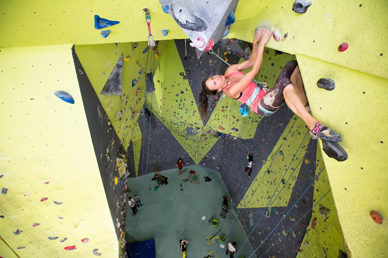 Woman rope climbing on a bright green wall