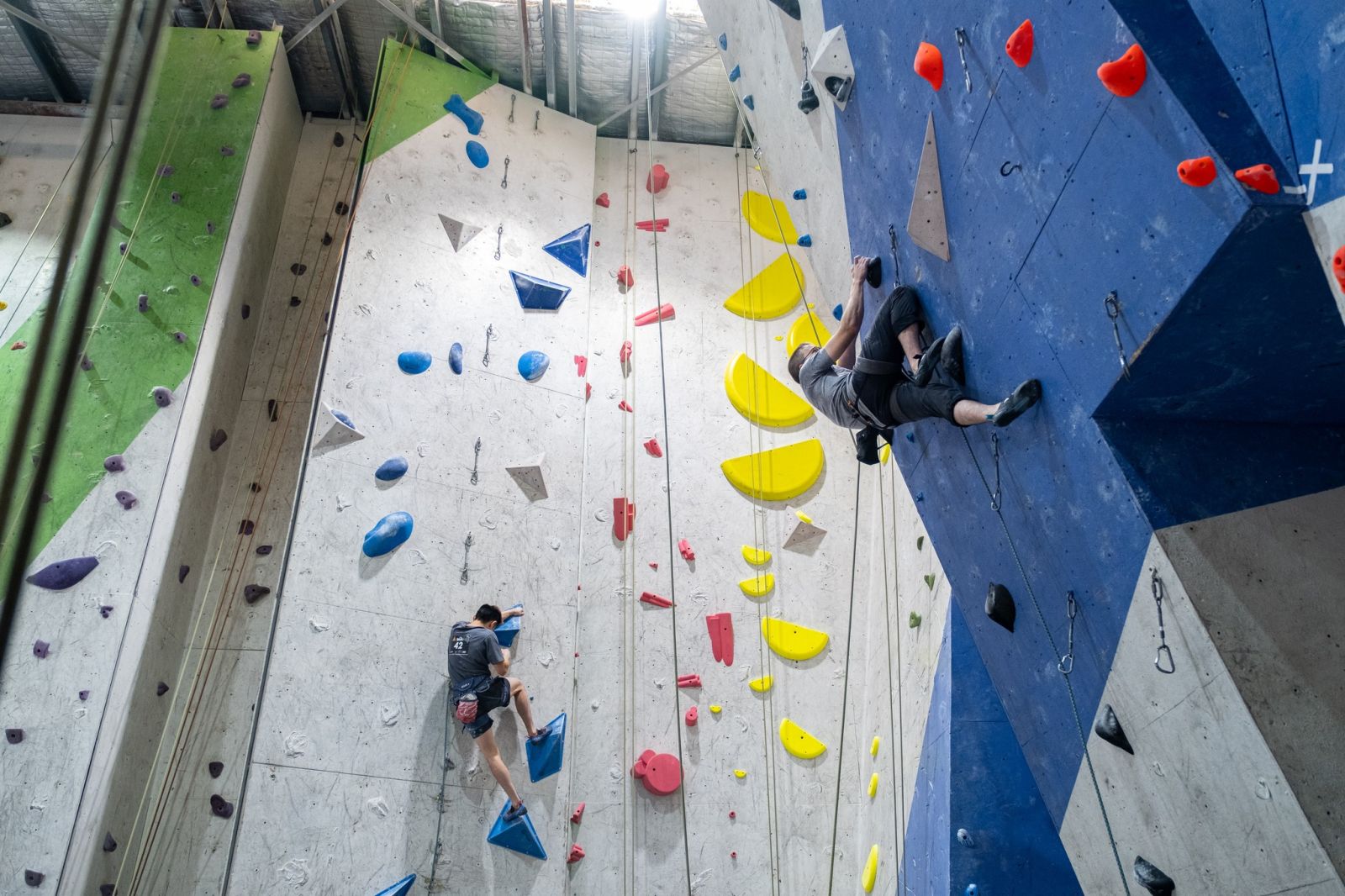 Two climbers top rope and lead climbing