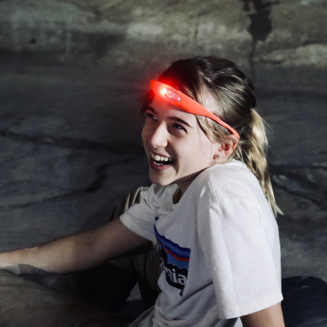 Ava at the base of the crag wearing a headlamp and Patagonia shirt.