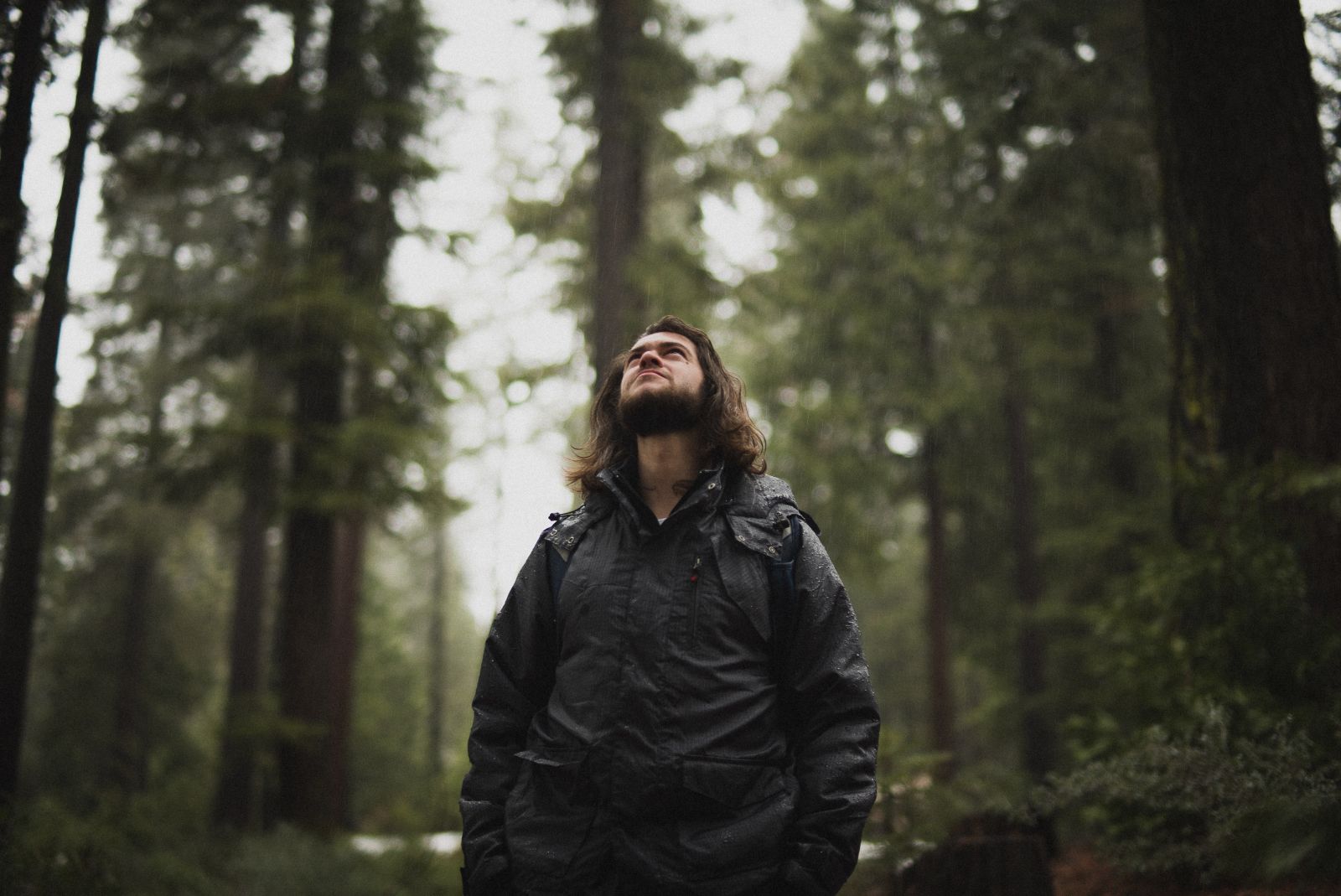 Man in his 30s wearing black rain jacket in the forest