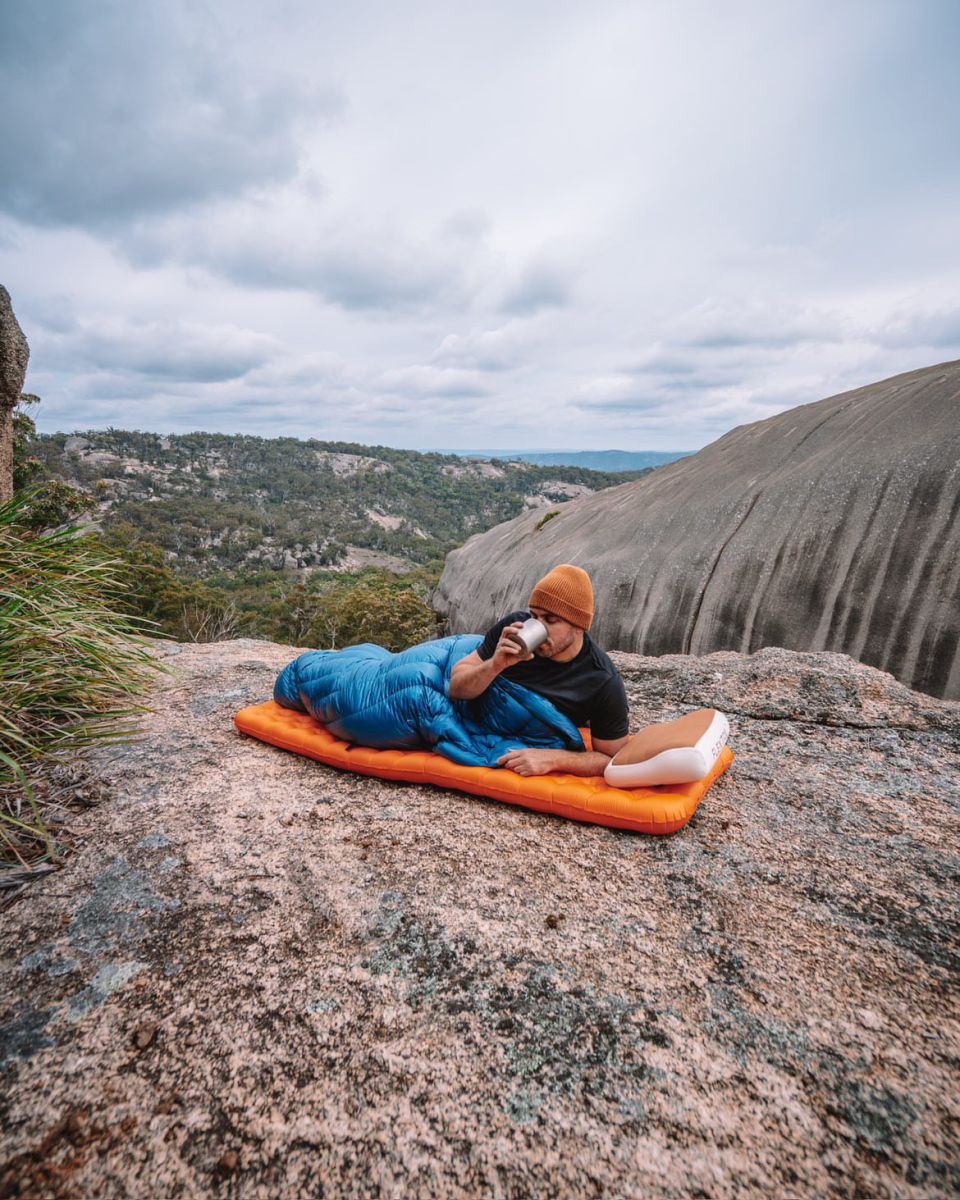 Paul laying on his Big Agnes sleeping pad drinking out of a camp cup