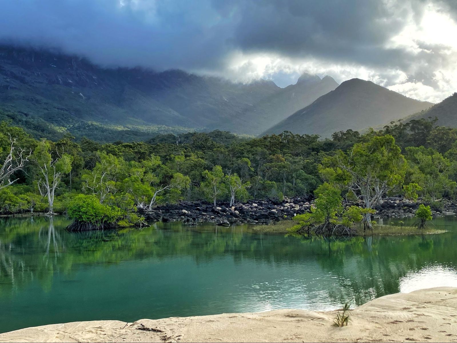 Lake with mountains in the background and the sun coming through the clouds