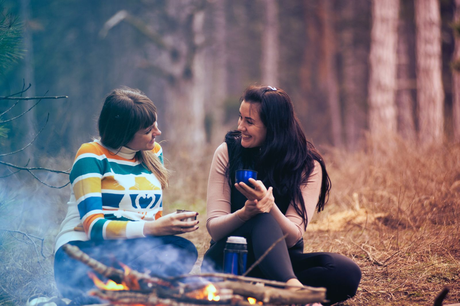 Two young adults chatting in the outdoors by a fire